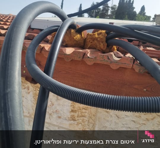 צינורות שחורים עם בידוד צהוב על גג רעפים